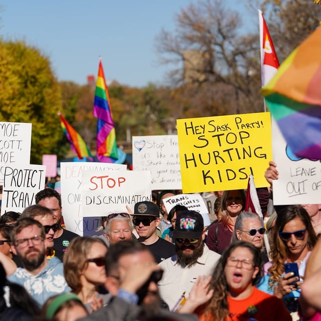 People hold signs while attending a rally against the Saskatchewan government's proposed legislation on pronoun policy in front of the Saskatchewan legislature in Regina, on Tuesday, Oct. 10, 2023. THE CANADIAN PRESS/Heywood Yu
