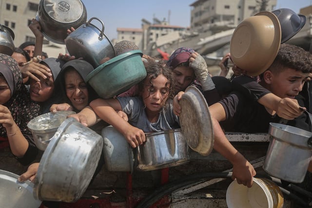 Hungry Palestinians in Gaza wait to receive food at an aid distribution site on August 10, 2025.