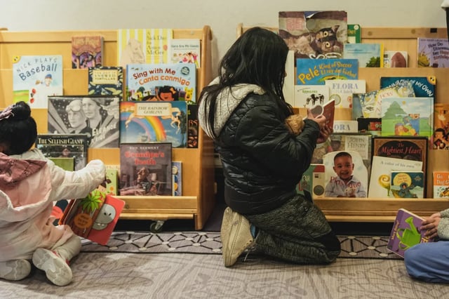 A girl in New York City looks at a book on a book shelf.