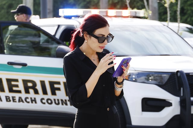 Laura Loomer uses her cell phone near Trump International Golf Club after police closed off the area following the apparent assassination attempt of Republican presidential nominee former President Donald Trump in West Palm Beach, Fla., Sunday, Sept. 15, 2024.