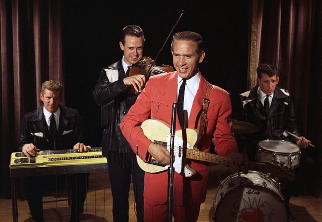 Buck Owens in his signature red jacket performs with his band, the Buckaroos.
