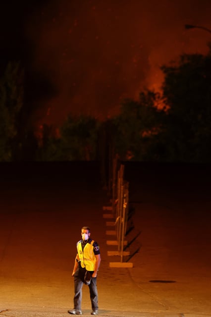 A police officer walks during a wildfire in Tres Cantos, near Madrid, Spain, August 11, 2025. REUTERS/Juan Medina