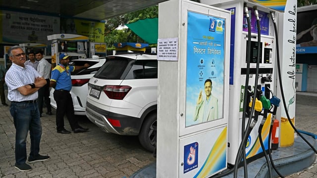 A man reads a notice announcing the ban on refuelling petrol cars older than 15 years and diesel vehicles older than 10 years, displayed at a gas station in New Delhi.