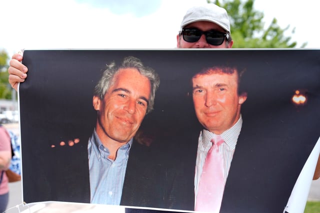 A protester holds up a photo of the future President Donald Trump with financier Jeffrey Epstein at a rally in Augusta, Georgia, on Aug. 2, 2025.