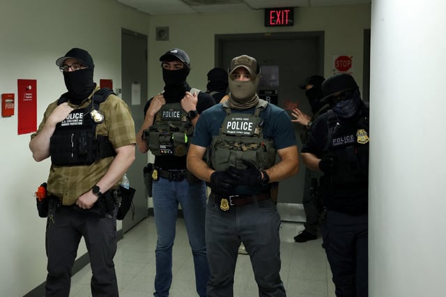 Federal officers wearing face coverings wait in a hallway outside of a courtroom at New York Federal Plaza Immigration Court inside the Jacob K. Javitz Federal Building in New York.