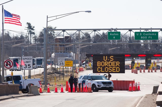 TOPSHOT - US Customs officers stand beside a sign saying that the US border is closed at the US/Canada border in Lansdowne, Ontario, on March 22, 2020. - The United States agreed with Mexico and Canada to restrict non-essential travel because of the coronavirus, COVID-19, outbreak and is planning to repatriate undocumented immigrants arriving from those countries. (Photo by Lars Hagberg / AFP) (Photo by LARS HAGBERG/AFP via Getty Images)