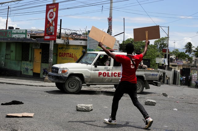 A man holds up placards as he yells toward a patrol car during a protest against gang-related violence and to demand the resignation of Haiti's transitional presidential council, in Port-au-Prince, Haiti, May 15, 2025. REUTERS/Jean Feguens Regala/File Photo