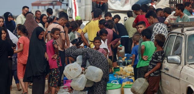 Des Palestiniens font la queue pour remplir des bidons d'eau, à al-Mawasi, dans le sud de la bande de Gaza, le 12 août 2025