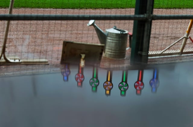 The Rate Field video board pinwheels are reflected in a rain puddle on a dugout railing during a rain delay for a White Sox-Phillies game on July 30, 2025. (John J. Kim/Chicago Tribune)