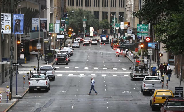 A solitary pedestrian crosses San Francisco&#39;s Battery Street, during a weekday in August of 2020, during the pandemic. The area would have previously been packed with people.