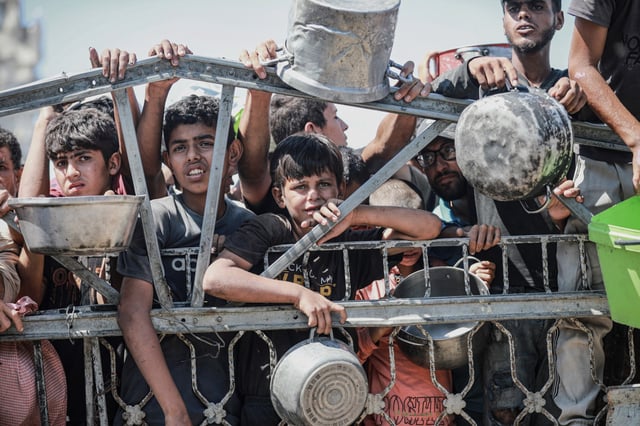Palestinians wait to receive hot meals in Gaza on Aug. 5, 2025.