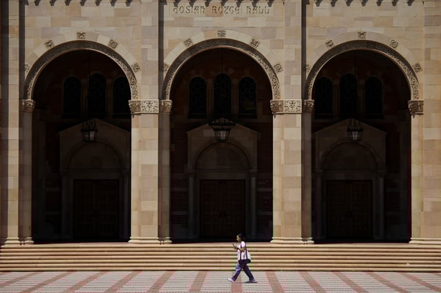 A woman walks by Royce Hall at the University of California Los Angeles (UCLA) in Los Angeles, California, U.S., August 11, 2025. REUTERS/Daniel Cole