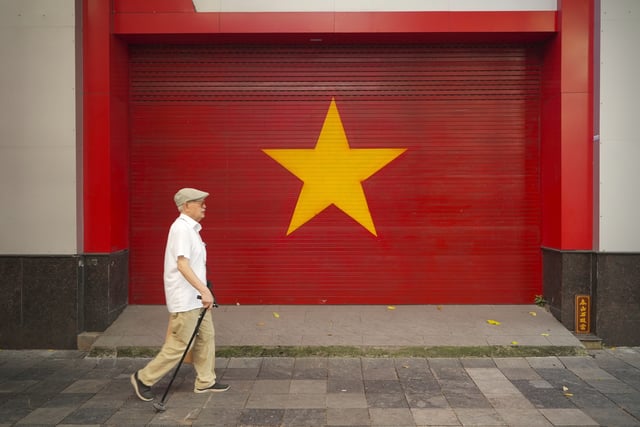 A man walks past a Vietnamese flag painted on a wall in Hanoi, Vietnam on August 12, 2025. (AP Photo/Hau Dinh)