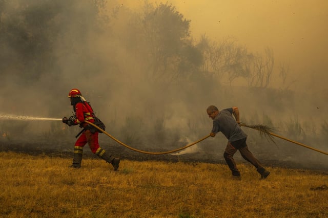 Un efectivo de la UME y un vecino colaboran durante el avance del fuego en el Macizo Central.