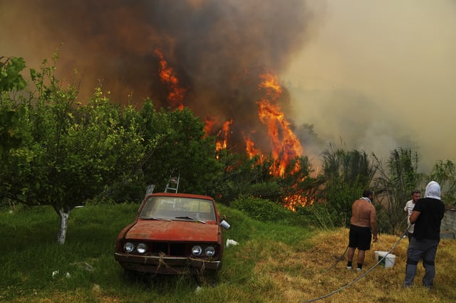 Men watch a wildfire in Vounteni, in the outskirts of Patras, western Greece, Wednesday, Aug. 13, 2025. (AP Photo/Thanassis Stavrakis)