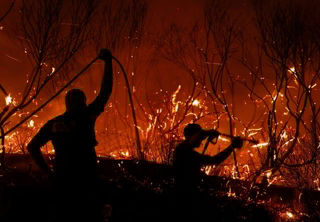 Firefighters try to extinguish a fire, as wildfire continues to burn in Delvina, Albania, August 12, 2025. REUTERS/Florion Goga
