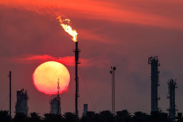 The sun sets behind burning gas flares at the Dora (Daura) Oil Refinery Complex in Baghdad on December 22, 2024.