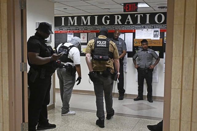 Agents wait to detain migrants coming for their hearings at an immigration court in New York.