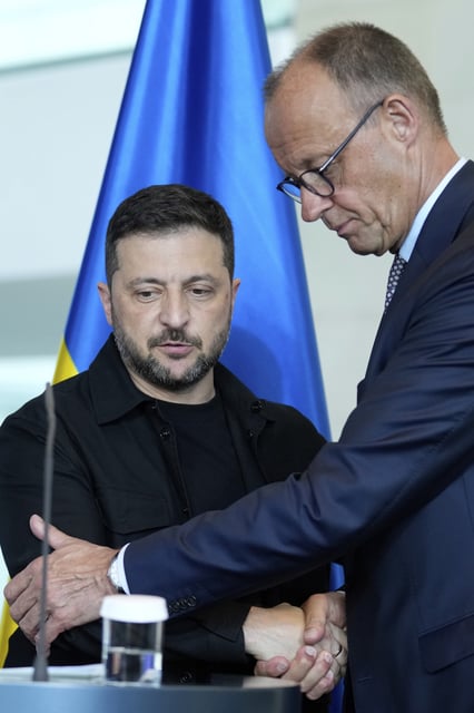 German Chancellor Friedrich Merz, right, and Ukrainian President Volodymyr Zelenskyy, left, shake hands after a joint press statement following talks with European and U.S. leaders in Berlin, Germany, Wednesday, Aug. 13, 2025. (AP Photo/Ebrahim Noroozi)
