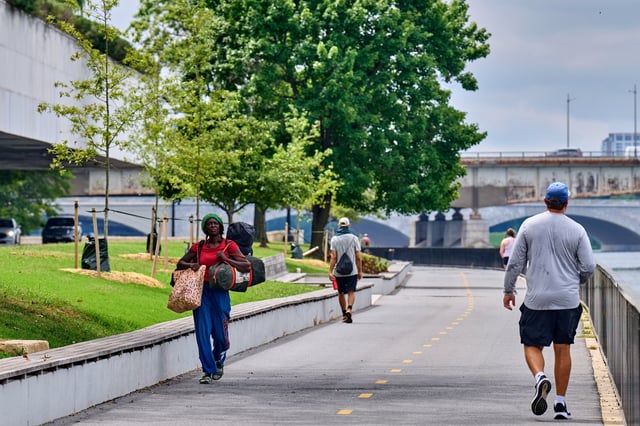 Caroline McIntyre, left, who is homeless, carries her belongings past the Kennedy Center, Wednesday, Aug. 13, 2025, in northwest Washington, as President Donald Trump makes an appearance there. She says her tent and belongings were taken from her last month in Washington. (AP Photo/Jacquelyn Martin)