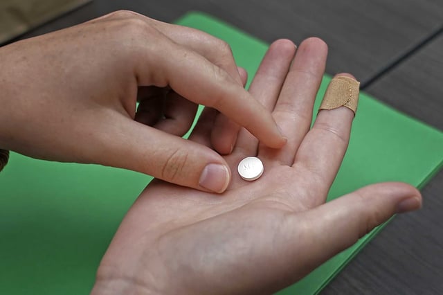 A patient prepares to take the first of two pills for a medication abortion during a visit to a clinic in Kansas City, Kan., on Wednesday, Oct. 12, 2022.