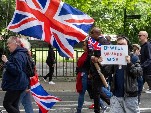 Supporters of Tommy Robinson, former leader of the far-right English Defence League, march holding Union Jacks and a sign referencing George Orwell during a demonstration in protest against what he considers to be a two-tier policing system on 1st June 2024 in London, United Kingdom. Tommy Robinson's Lawfare documentary was shown during the rally which followed the march. (photo by Mark Kerrison/In Pictures via Getty Images)
