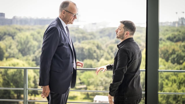 Friedrich Merz und Wolodymyr Selenskyj unterhalten sich vor einer Balkonbrüstung