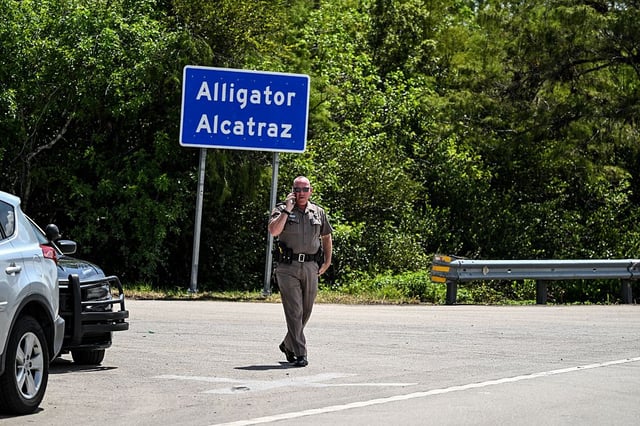 A Florida highway patrol officer looks on as protesters gather to demand the closure of the immigrant detention center known as 'Alligator Alcatraz' at the Dade-Collier Training and Transition Airport in Ochopee, Fla., on July 22, 2025. Immigrants held at U.S. detention centres have experienced abusive and degrading treatment, a Human Rights Watch report said on July 21.