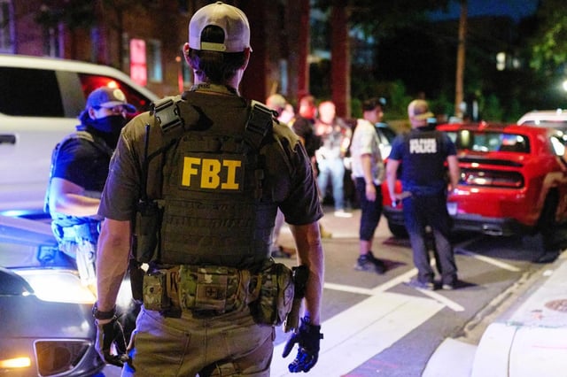 Oficiales de varias agencias federales, incluidos el FBI y la Policía de Parques, interrogan a una pareja que estaba comiendo afuera de un estacionamiento, el martes 12 de agosto de 2025, en el noroeste de Washington, cerca de Kennedy St. NW. La pareja fue liberada después que les registraron el automóvil. (AP Foto/Jacquelyn Martin)