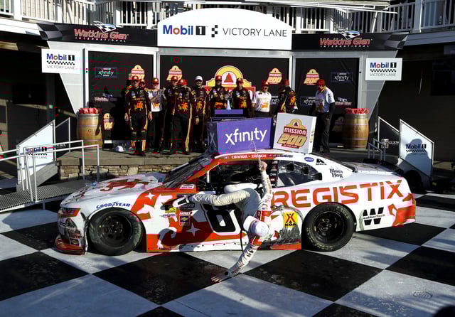 Aug 9, 2025; Watkins Glen, New York, USA; NASCAR Xfinity Series driver Connor Zilisch falls from his race car while celebrating in victory lane after winning the Mission 200 at The Glen at Watkins Glen International. Mandatory Credit: Matthew O'Haren-Imagn Images
