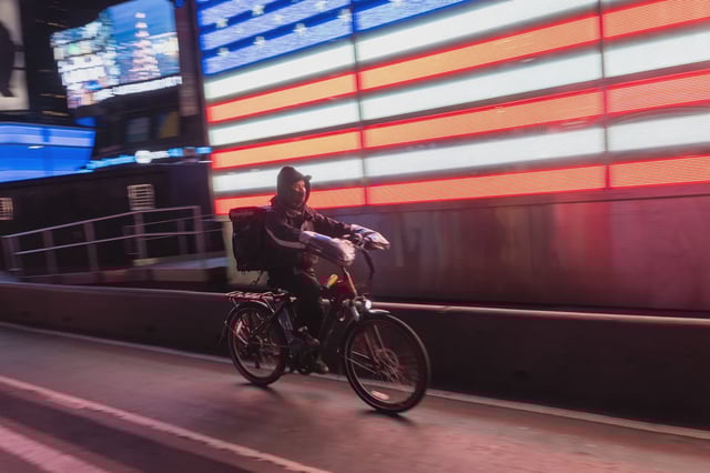 A food delivery worker uses an electric bicycle in Times Square on February 06, 2024 in New York City.