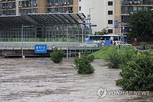 Vehicles cross a bridge in northern Seoul over the Jungnang Stream, which has swelled due to heavy rain, on Aug. 13, 2025. (Yonhap)