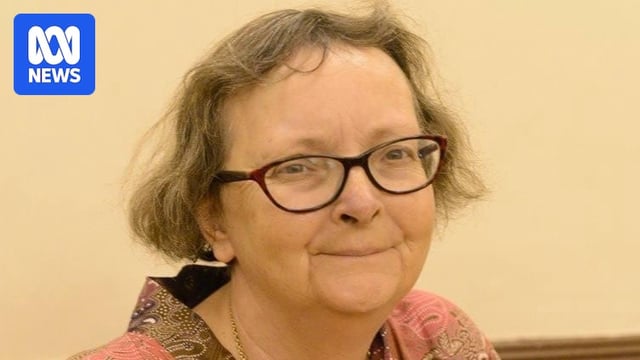 A smiling woman wearing glasses and short hair.