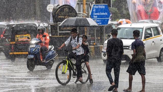 Commuters using umbrellas during rain in Mumbai, Maharashtra