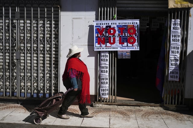 A woman walks past a campaign center for supporters of former President Evo Morales who are in favor or a null vote in the upcoming presidential election in El Alto, Bolivia, Tuesday, Aug. 12, 2025. (AP Photo/Natacha Pisarenko)