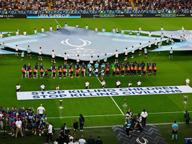 Die UEFA rollt vor dem Supercup ein Banner zur Unterstützung von Kindern in Kriegsgebieten aus.