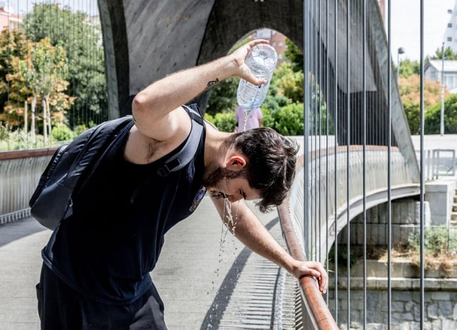 Un hombre se alivia del calor echándose agua. |  Ricardo Rubio