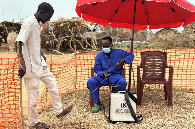 Un employé désinfecte les pieds d'un homme à l'entrée d'une unité d'isolement pour les malades du choléra, à Tawila dans l'ouest du Soudan le 12 août 2025
