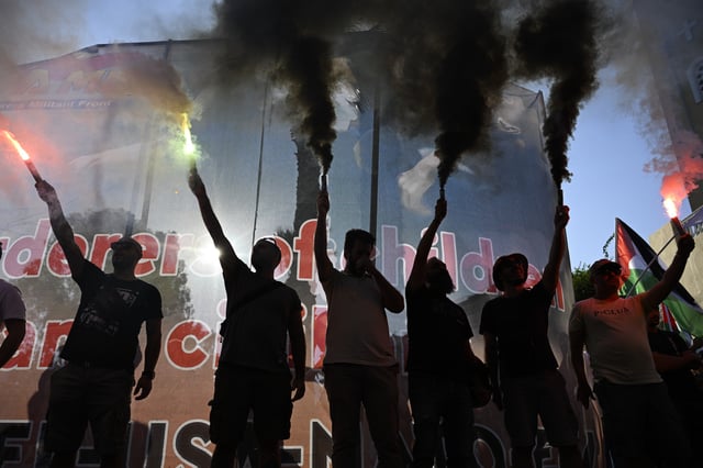 Protesters hold flares during a rally to protest the arrival of a cruise ship with Israelis, in Piraeus port, Greece, Thursday, Aug. 14, 2025. (AP Photo/Michael Varaklas)