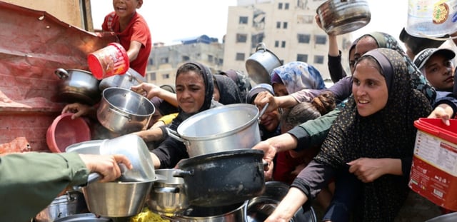 Des Palestiniens tentent de recevoir de la nourriture lors d'une distribution à Gaza le 13 août 2025