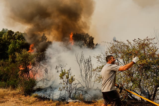A man tries to put out a wildfire in Larouco, northwestern Spain, Wednesday, Aug. 13, 2025. (AP Photo/Lalo R. Villar)