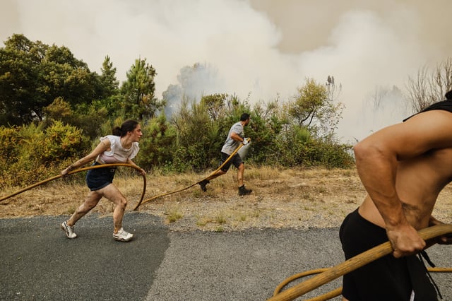 Local residents and volunteers work together to put out an encroaching wildfire in Larouco, northwestern Spain, Wednesday, Aug. 13, 2025. (AP Photo/Lalo R. Villar)