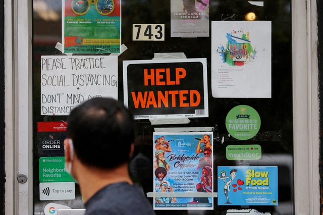 A pedestrian passes a "Help Wanted" sign in the door of a hardware store in Cambridge, Massachusetts, U.S., July 8, 2022. REUTERS/Brian Snyder/File Photo