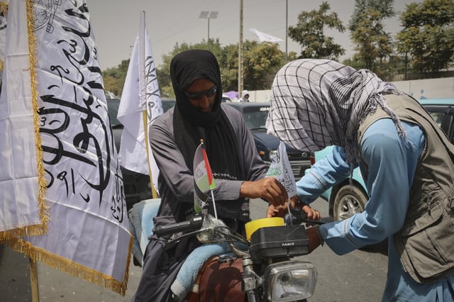 A man decorates his motorcycle with Taliban and Palestinian flags ahead of celebrations marking the fourth anniversary of the US withdraw from Afghanistan and the start of the Taliban rule in Kabul, Afghanistan, Thursday Aug. 14 , 2025. (AP Photo/Siddiqullah Alizai)