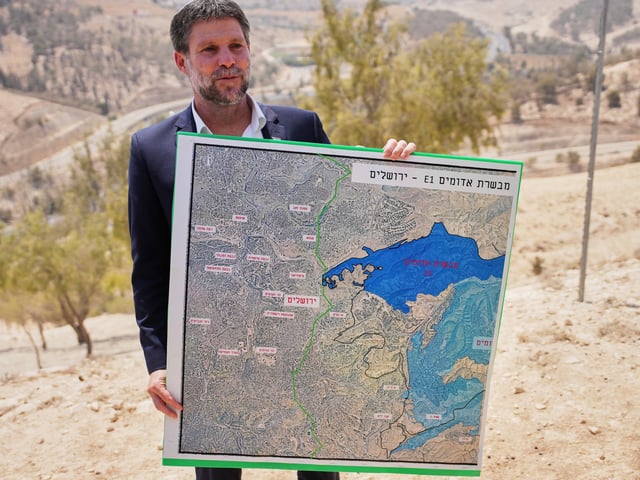 CORRECTS DAY Israeli Finance Minister Bezalel Smotrich holds a map that shows the E1 settlement project during a press conference near the settlement of Maale Adumim, in the Israeli-occupied West Bank, Thursday, Aug. 14, 2025. (AP Photo/Ohad Zwigenberg)