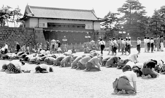 ARCHIVO - Japoneses se arrodillan frente al Palacio Imperial de Tokio al momento en que el emperador Hirohito anuncia por radio la derrota de Japón en la Segunda Guerra Mundial, el 15 de agosto de 1945. (Kyodo New vía AP, archivo)