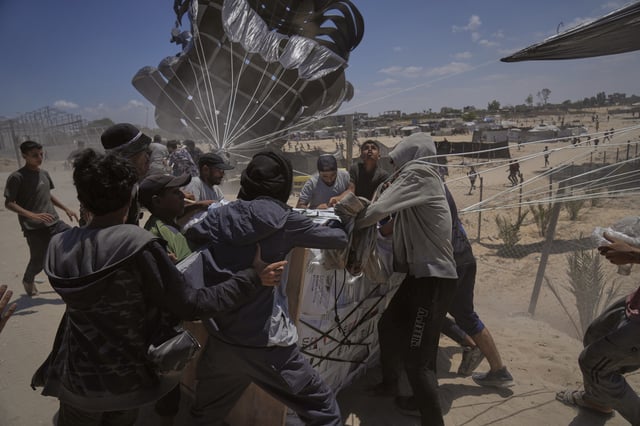 FILE - Palestinians rush to collect humanitarian aid airdropped by parachutes into Deir al-Balah, central Gaza Strip, Tuesday, Aug. 5, 2025. (AP Photo/Abdel Kareem Hana, File)