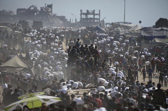 FILE - Palestinians carry sacks of flour taken from a humanitarian aid convoy en route to Gaza City, on the outskirts of Beit Lahiya, northern Gaza Strip, Friday, Aug. 1, 2025. (AP Photo/Jehad Alshrafi, File)