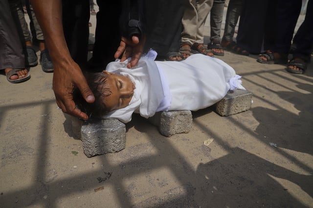 The body of 5-year-old Jamal al-Najjar is placed on the ground atop bricks before a funeral prayer after he died at Nasser Hospital in Khan Younis, southern Gaza Strip, Tuesday, Aug. 12, 2025. The head of Nasser's pediatrics unit said Jamal, who was born with rickets, died from severe malnutrition. (AP Photo/Mariam Dagga)