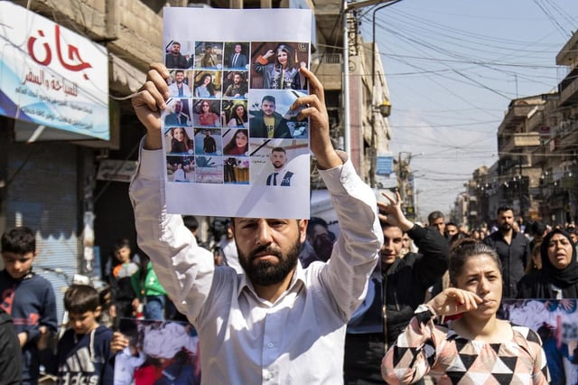Un homme défile avec une pancarte représentant un collage de photos de victimes d’une récente vague de violences visant la minorité alaouite de Syrie, dans l’ouest de la Syrie, le 11 mars 2025.